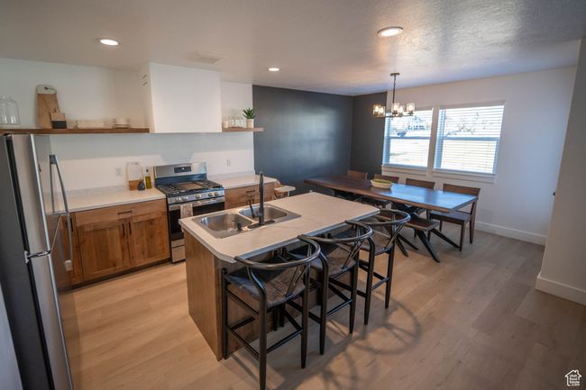 Stunning modern kitchen featuring stylish open floating shelves that blend form and function—perfect for showcasing your favorite dishware and accessories. A sleek modern range hood pairs effortlessly with premium stainless steel appliances, while warm | Image 9