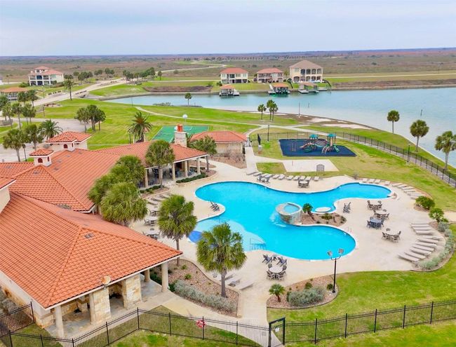 Community pool with a patio area, fence, a lawn, and a water view | Image 5