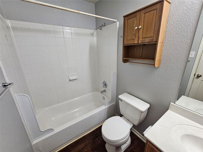 Bathroom with a textured wall, vanity, wood finished floors, and shower / bathtub combination | Image 28