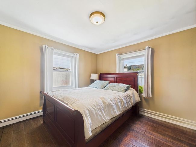 Bedroom featuring wood finished floors, a baseboard heating unit, and ornamental molding | Image 21