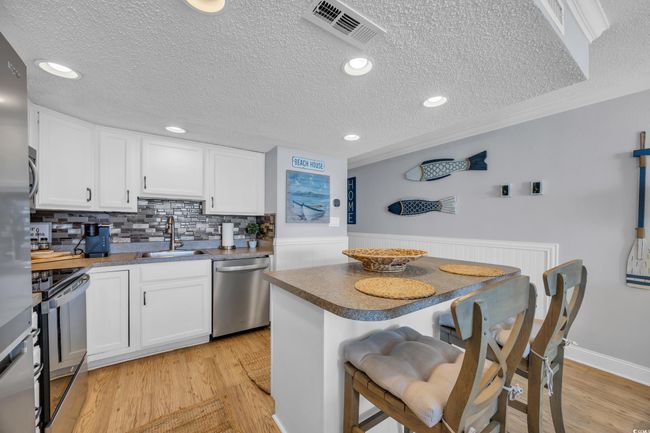 Kitchen with stainless steel appliances, a sink, a textured ceiling, tasteful backsplash, and white cabinetry | Image 17