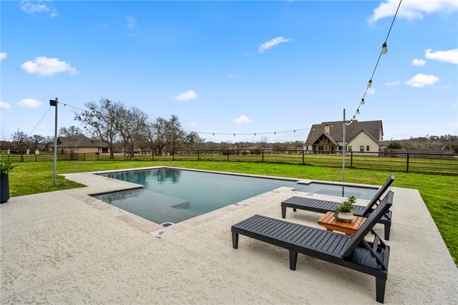 View of swimming pool with a patio area, a fenced backyard, a fenced in pool, and a yard | Image 49