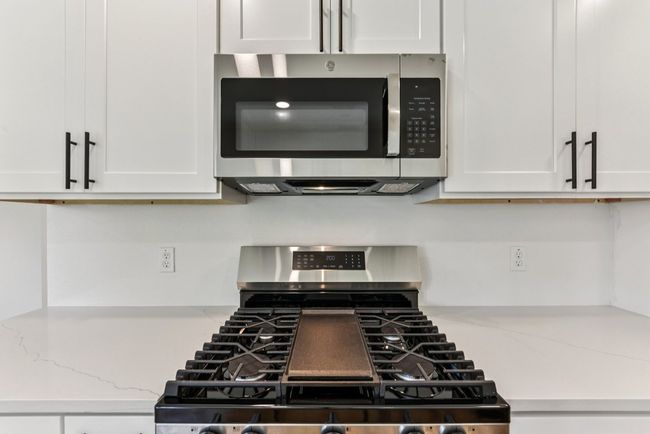 Kitchen with appliances with stainless steel finishes, light stone counters, and white cabinetry | Image 11