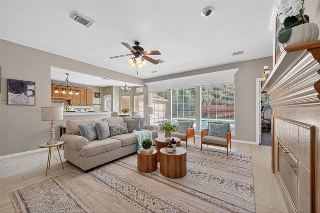 This photo showcases a welcoming entryway with a rich wooden front door featuring decorative glass. The space has natural light from side windows with blinds, elegant wainscoting, and hardwood flooring. A framed artwork and decorative wall piece add charm, creating a warm and inviting first impression. | Image 9