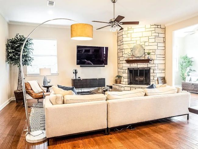 Living room with wood finished floors, ornamental molding, visible vents, a ceiling fan, and plenty of natural light | Image 21