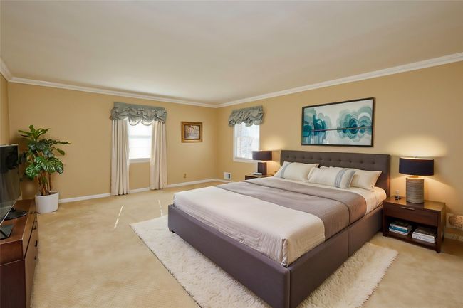 Bedroom featuring light colored carpet, crown molding, and baseboards | Image 8