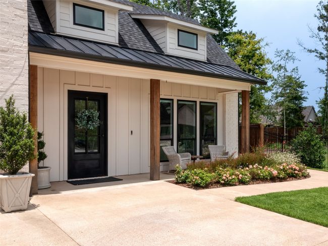 View of exterior entry with board and batten siding, a standing seam roof, roof with shingles, a patio area, and a metal roof | Image 5