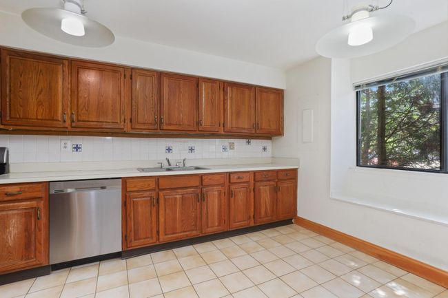 Kitchen with stainless steel dishwasher, a sink, light countertops, tasteful backsplash, and brown cabinetry | Image 4