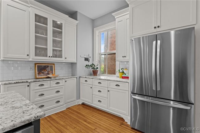 Kitchen with backsplash, freestanding refrigerator, glass insert cabinets, and white cabinetry | Image 15