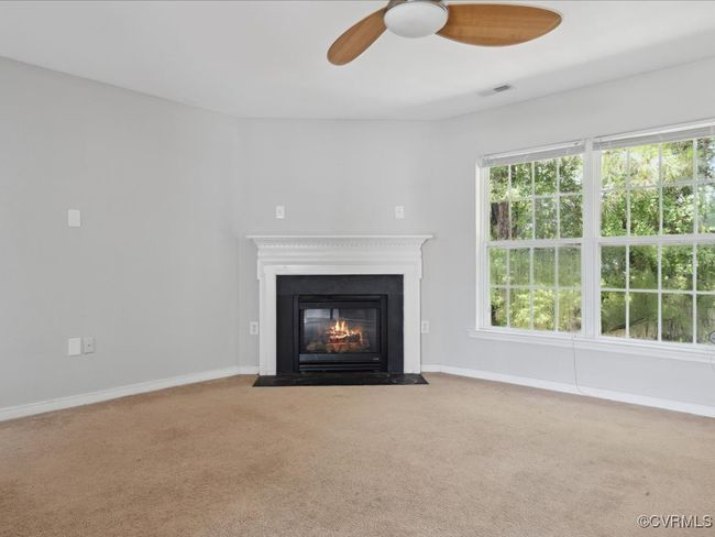 Unfurnished living room with carpet, a ceiling fan, and a fireplace with flush hearth | Image 12