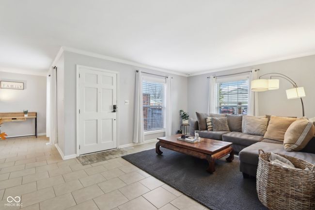 living area with crown molding, baseboards, and light tile patterned floors | Image 4