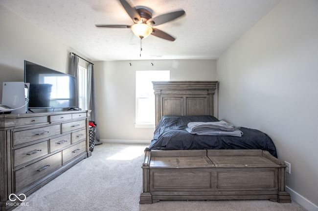 bedroom featuring light colored carpet, a textured ceiling, and a ceiling fan | Image 19