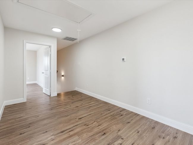 Spare room with attic access, wood finished floors, visible vents, and baseboards | Image 18