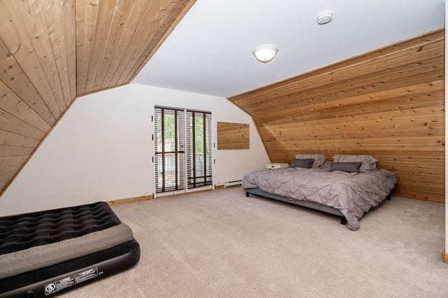 Bedroom featuring carpet flooring, baseboard heating, vaulted ceiling, and wood ceiling | Image 36