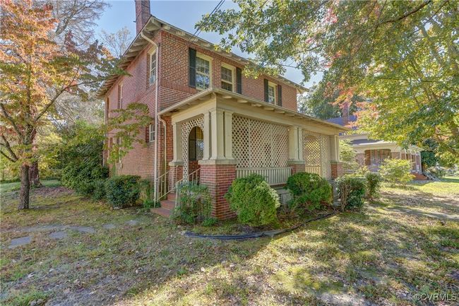 View of property exterior featuring covered porch, brick siding, and a chimney | Image 5