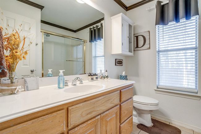 Full bath featuring crown molding, a stall shower, vanity, toilet, and tile patterned flooring | Image 8