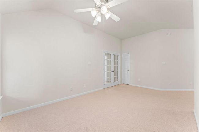 Accessible through elegant French doors, this spacious extra room connected to the primary room offers endless versatility. It's ideal for a home office, reading lounge, fitness space, or nursery. Vaulted ceilings and neutral tones create a bright, open feel that complements the primary suite beautifully. | Image 24