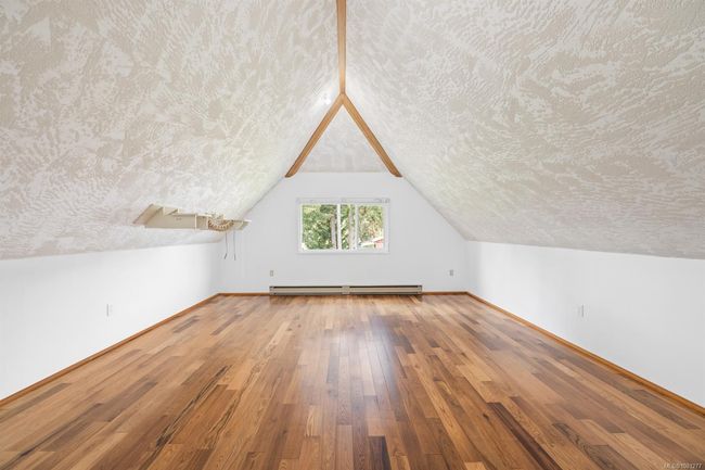 Additional living space with a baseboard radiator, wood-type flooring, a textured ceiling, baseboards, and lofted ceiling | Image 21