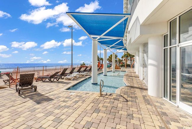 Community pool with a water view, a hot tub, a patio area, and a view of the beach | Image 36