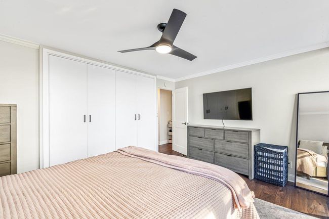 Bedroom featuring dark wood-style flooring, ornamental molding, a closet, and a ceiling fan | Image 6
