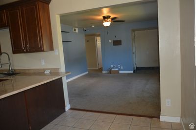 Kitchen with ceiling fan, dark brown cabinets, light carpet, and sink | Image 3