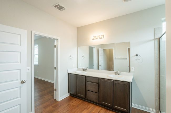 Full bathroom with double vanity, visible vents, a sink, and wood finished floors | Image 26