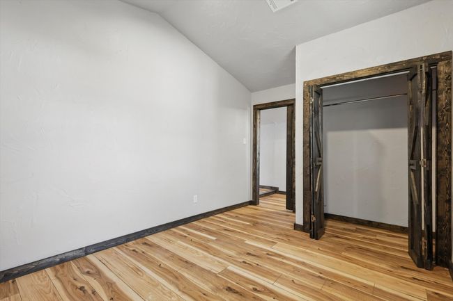 Unfurnished bedroom featuring light wood-type flooring, baseboards, visible vents, and vaulted ceiling | Image 24