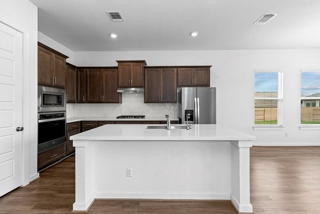 Kitchen featuring appliances with stainless steel finishes, a sink, dark wood-style floors, a kitchen island with sink, and recessed lighting | Image 8