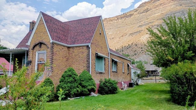 View of side of home with brick siding, a chimney, and roof with shingles | Image 4