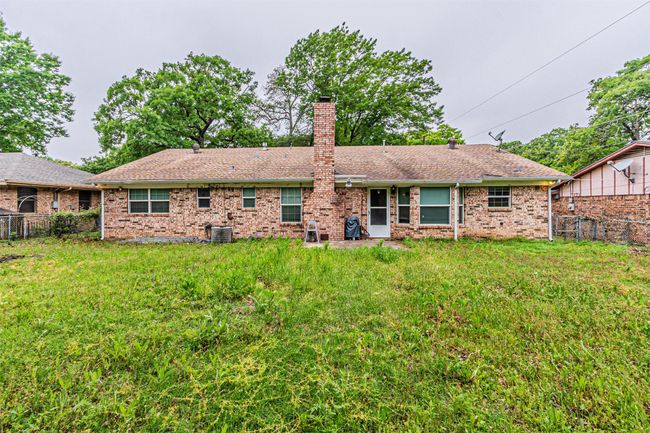 Back of house featuring a chimney, a fenced backyard, a yard, brick siding, and cooling unit | Image 32