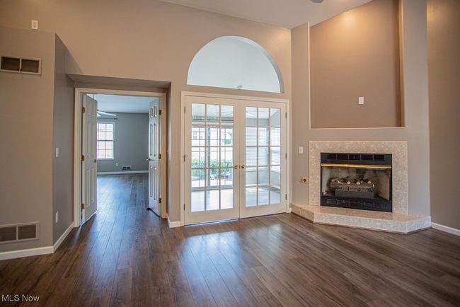 Unfurnished living room with a fireplace, french doors, dark wood-type flooring, and a high ceiling | Image 17