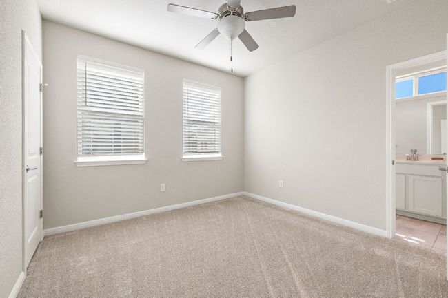 Unfurnished bedroom featuring light colored carpet, baseboards, connected bathroom, and ceiling fan | Image 20