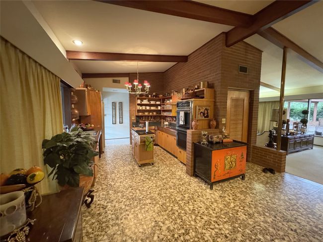Kitchen with beamed ceiling, open shelves, a chandelier, dark countertops, and hanging light fixtures | Image 27