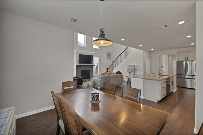 Dining area featuring dark wood finished floors, a fireplace with raised hearth, baseboards, and visible vents | Image 11