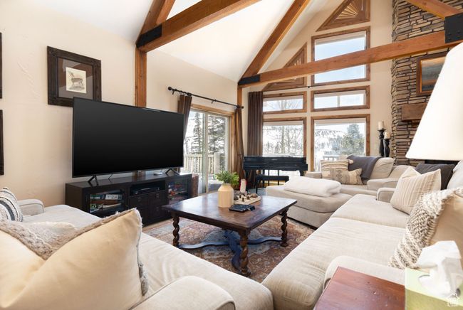 Living room with high vaulted ceiling, a stone fireplace, and beam ceiling | Image 26