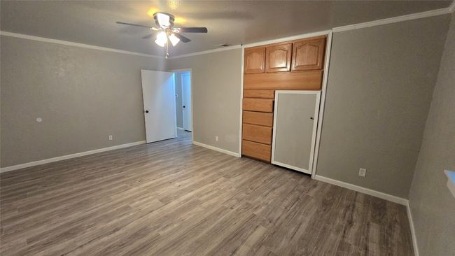 Unfurnished bedroom with wood finished floors, crown molding, and ceiling fan | Image 10