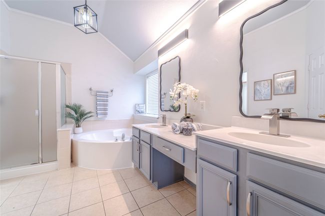 Full bathroom featuring double vanity, a bath, a stall shower, tile patterned floors, and vaulted ceiling | Image 27