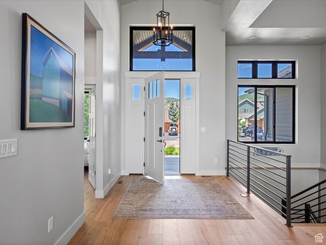 Entrance foyer featuring a chandelier, baseboards, wood finished floors, and a towering ceiling | Image 7
