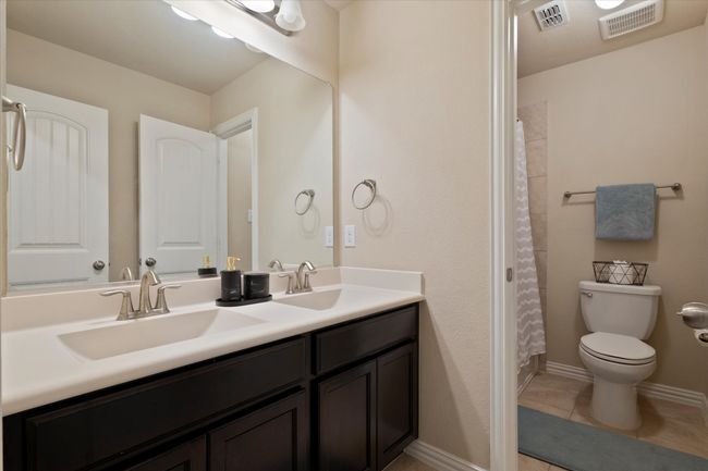 Bathroom with toilet, double vanity, tile patterned floors, and a shower with shower curtain | Image 26