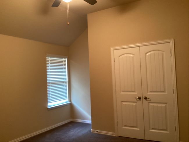 Unfurnished bedroom with dark carpet, a closet, vaulted ceiling, baseboards, and a ceiling fan | Image 32