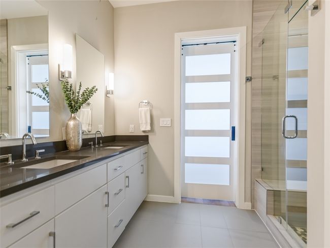 Huge walk-in glass wall shower features upgraded shower heads. The custom installed sliding barn door is designed for both privacy and natural light. | Image 17
