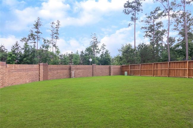 Spacious backyard with lush green lawn, surrounded by a mix of wooden and brick privacy fencing, offering a serene and private outdoor space. | Image 44