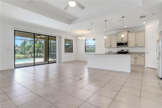 Kitchen with stainless steel appliances, baseboards, open floor plan, cream cabinetry, and a sink | Image 23