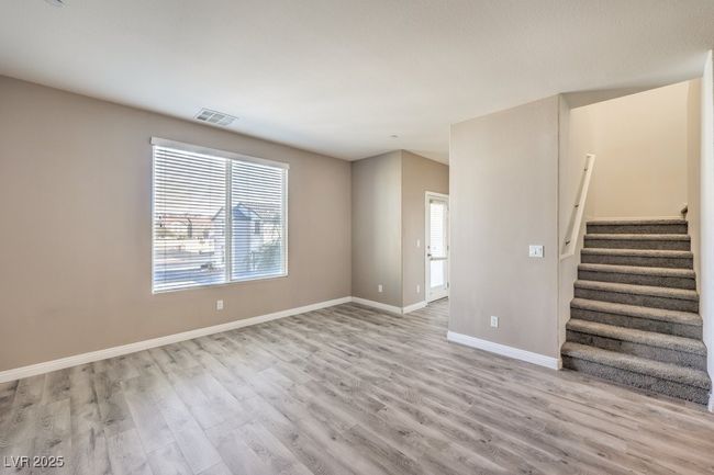 Unfurnished living room featuring baseboards, visible vents, stairway, and light wood finished floors | Image 27