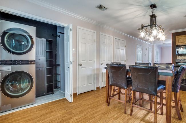 Dining space with stacked washer / dryer, crown molding, light wood-type flooring, and a chandelier | Image 13