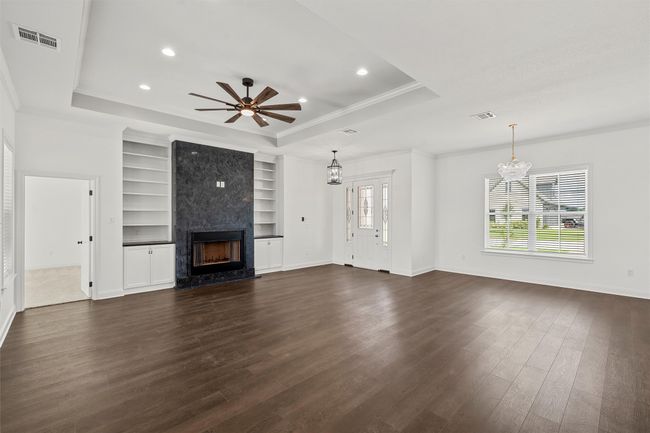 Unfurnished living room with a tray ceiling, ornamental molding, a chandelier, dark wood-type flooring, and a premium fireplace | Image 5