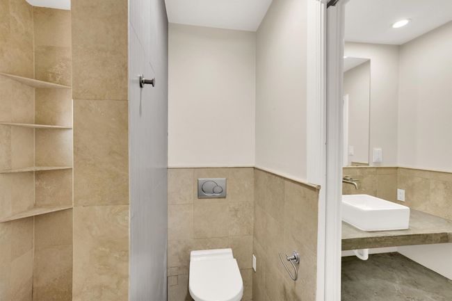 Bathroom with tile walls, wainscoting, a sink, and toilet | Image 28