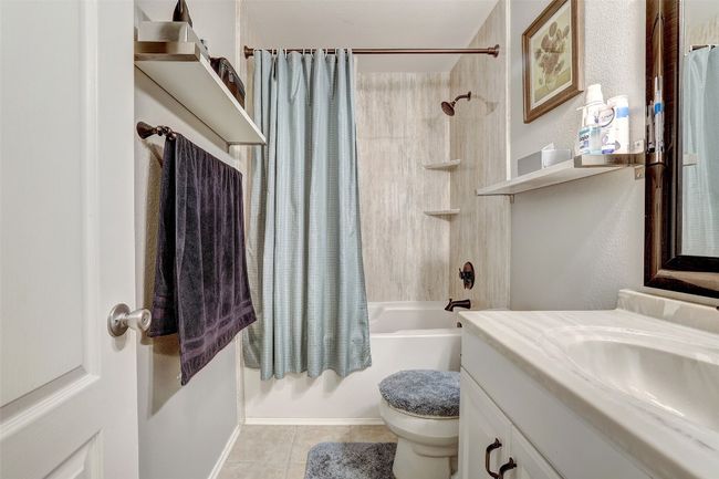 Full bath featuring tile patterned flooring, shower / bathtub combination with curtain, vanity, and toilet | Image 23