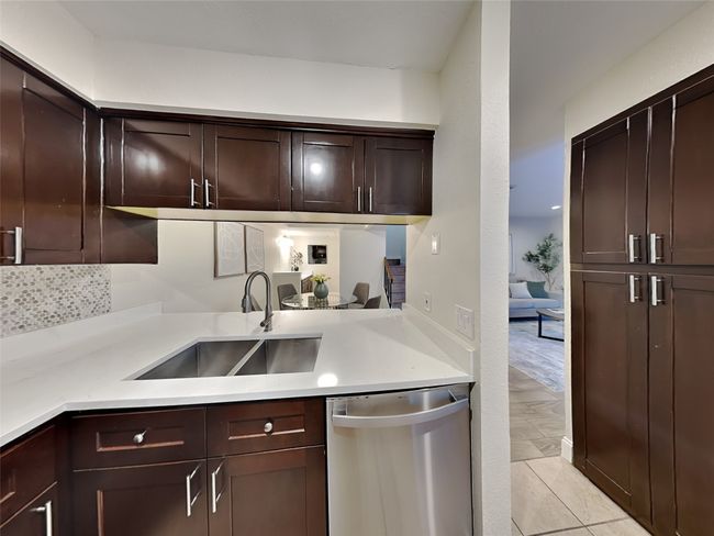 Kitchen with stainless steel dishwasher, a sink, dark brown cabinetry, backsplash, and light countertops | Image 10