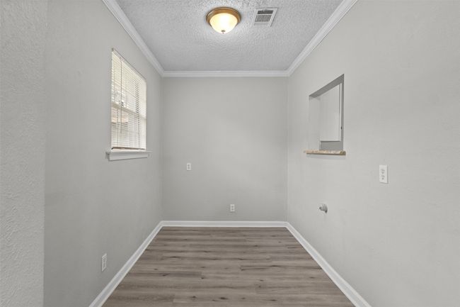 Unfurnished room featuring visible vents, a textured ceiling, crown molding, and wood finished floors | Image 13